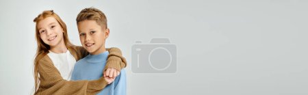 niños pequeños con atuendos casuales abrazándose y sonriendo a la cámara sobre fondo gris, moda, pancarta