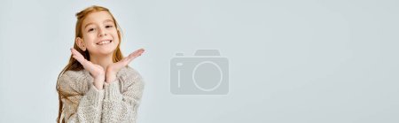 pretty little girl in casual sweater looking at camera, hands under face, fashion concept, banner