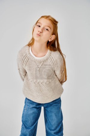 jolly preadolescent girl in knitted trendy sweater looking at camera with pouted lips, fashion