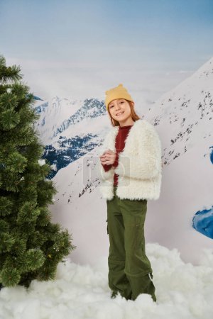 plan vertical de preteen fille gaie en hiver tenue élégante souriant à la caméra debout sur la neige