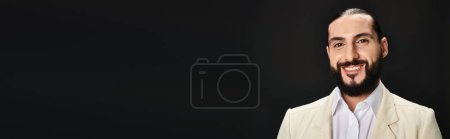 Photo for Happy and bearded arabic man in white shirt and blazer looking at camera on black background, banner - Royalty Free Image
