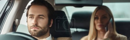 Foto de Hombre barbudo guapo conduciendo coche con mujer de negocios rubia hablando por teléfono móvil, pancarta - Imagen libre de derechos