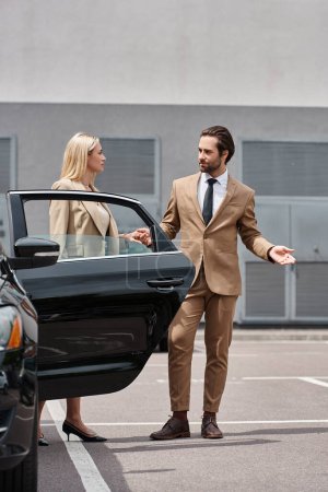 stylish handsome businessman and elegant woman holding hands near luxury car on city street