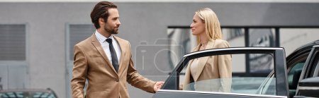 bearded stylish man and elegant blonde businesswoman holding hands near luxury car on street, banner