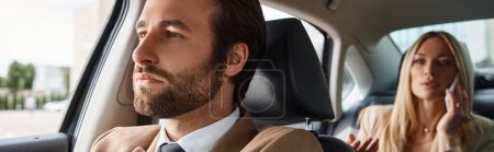 elegant man in suit driving luxury car with blonde businesswoman talking on smartphone, banner