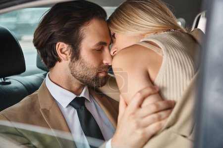 passionate and elegant business couple in formal wear embracing while traveling in car, romance