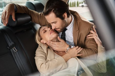stylish man in suit embracing blonde passionate businesswoman while traveling in car, seduction