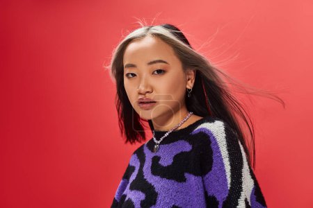 Foto de Hermosa joven asiático modelo en vibrante suéter con animal print con corazón en forma de collar en rojo - Imagen libre de derechos