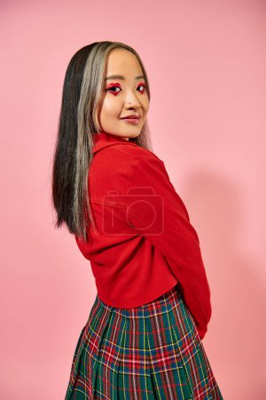 asian young woman in valentines day red jacket posing on pink background, heart shape eye makeup