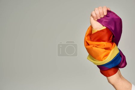 Foto de Vista recortada de la mano de una persona no binaria con bandera LGBT sobre fondo gris con espacio para copiar - Imagen libre de derechos