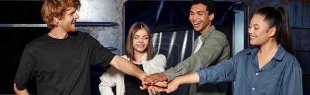 grupo multicultural joven de amigos que apilan las manos mientras tienen búsqueda en la sala de escape, pancarta