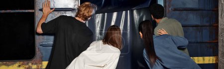 back view banner of multiracial friends looking inside of subway wagon during quest in escape room