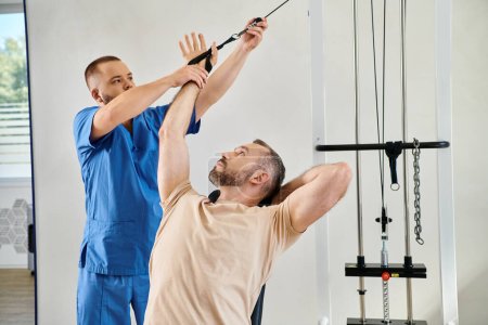 Photo for Skilled doctor assisting man during recovery training on exercise machine in kinesio center - Royalty Free Image