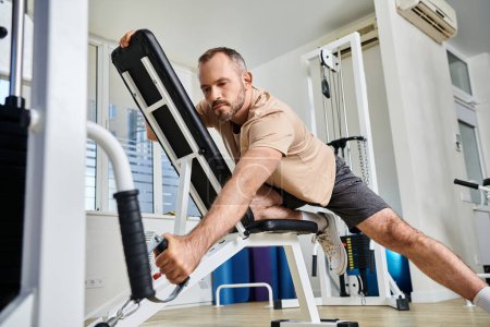 Photo for Bearded man in sportswear training on exercise machine in modern gym of kinesio center, recovery - Royalty Free Image