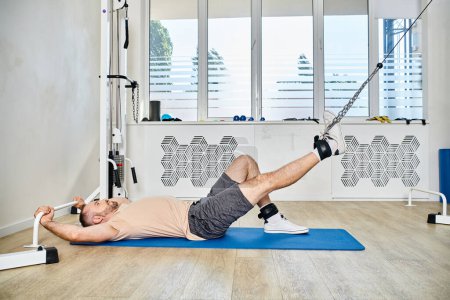 Photo for Side view of sportive man lying down on fitness mat during recovery training in kinesio center - Royalty Free Image