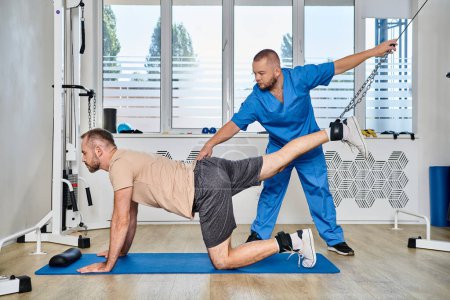 Photo for Skilled physiotherapist assisting man training during recovery session in gym of kinesio center - Royalty Free Image