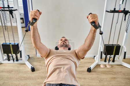 Photo for Athletic man in sportswear working out on exercise machine in kinesio center, recovery session - Royalty Free Image