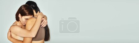 Photo for Young woman with closed eyes embracing her friend while showing support on grey background, banner - Royalty Free Image