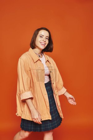 Photo for Jolly young woman with short hair looking at camera and smiling on orange background, carefree - Royalty Free Image
