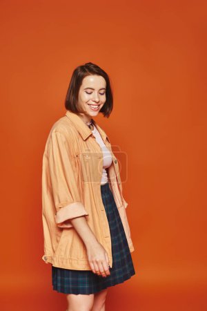 Photo for Carefree young woman with short hair looking at camera and smiling on orange background, emotion - Royalty Free Image