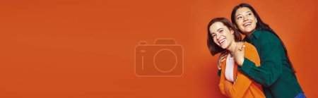 Photo for Friends in casual clothing hugging and sharing happy moment together on orange background, banner - Royalty Free Image