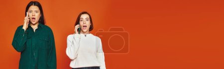 Transparent, schockierte multikulturelle Frauen in lebendiger Kleidung, die auf orangefarbenem Hintergrund über Mobiltelefone sprechen
