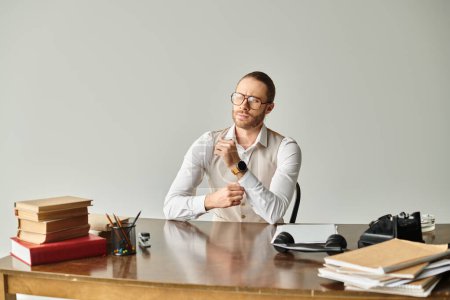 concentrated good looking man with beard and glasses sitting at table while working hard in office