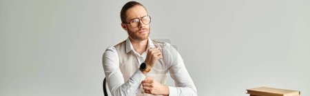 handsome focused man with beard and glasses sitting at table while working hard in office, banner