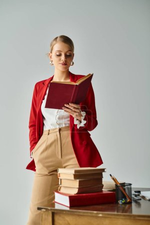 alluring woman with blonde hair in vivid attire reading next to pile of books with hand in pocket