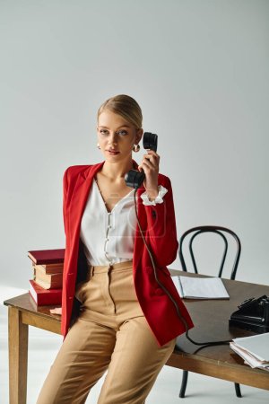 gut aussehende blonde Frau in lebendiger Kleidung spricht per Retro-Telefon und schaut im Büro weg