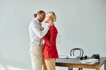 appealing young couple in elegant stylish outfits kissing lovingly while in office, work affair