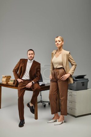 attractive young couple in elegant clothes posing together at office and looking at camera, affair