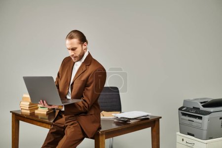 attraktiver junger Mann mit Bart in modischer brauner Jacke arbeitet im Büro an seinem Laptop