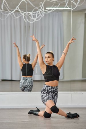 Una bailarina elegante en tacones altos y vestimenta activa en blanco y negro, con gracia equilibra en una rodilla