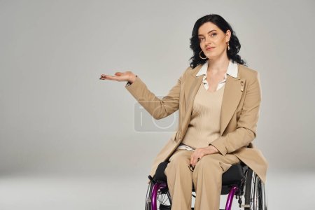 good looking woman with disability in wheelchair in pastel suit gesturing and looking at camera