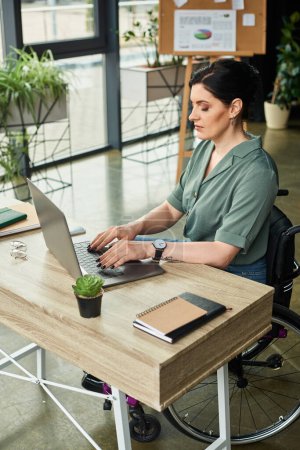 attrayant femme d'affaires avec handicap en fauteuil roulant travaillant dur sur son ordinateur portable au bureau