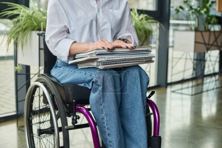 vista recortada de la dedicada mujer de negocios discapacitada en silla de ruedas que sostiene su papeleo mientras está en el cargo