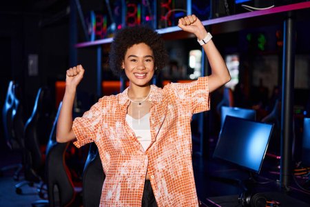 african american woman in vibrant clothing, her face radiating with joy and standing with arms up