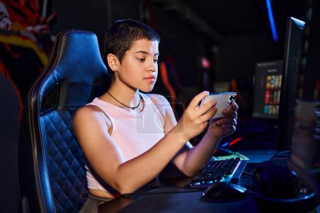 Foto de Una mujer enfocada se sienta cómodamente en su computadora, mientras se sumerge en el mundo digital por teléfono - Imagen libre de derechos