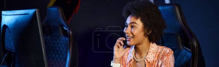 happy black woman sits at her computer and having phone call near computer, cybersport banner