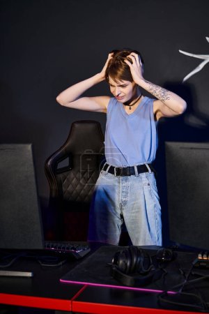 mujer frustrada con tatuaje en la mano mirando a la computadora y estresándose, jugador derrotado