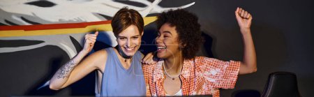 Téléchargez les photos : Amis féminines heureuses multiculturelles regardant l'écran d'ordinateur et célébrant la victoire, bannière - en image libre de droit