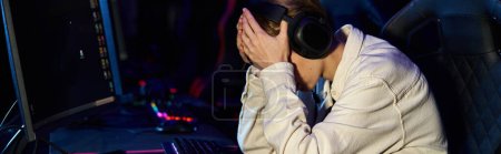 Téléchargez les photos : Joueur bouleversé dans les écouteurs avec les mains sur le visage après un match de cybersport perdant, bannière de déception - en image libre de droit