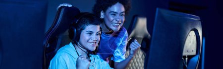 excited and young interracial women winning a game in a cybersport play session, horizontal banner