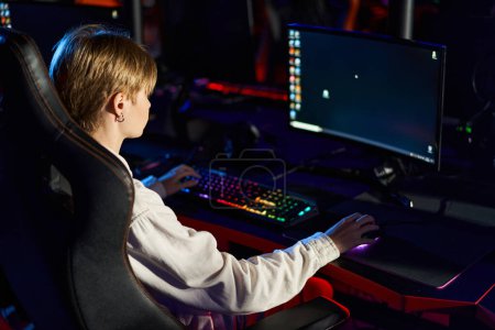 Téléchargez les photos : Joueur jouant à des jeux de cybersport sur un ordinateur avec un écran vif, clavier avec éclairage - en image libre de droit