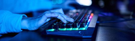 banner de las manos femeninas recortadas escribiendo en el teclado de la computadora con iluminación, luz azul