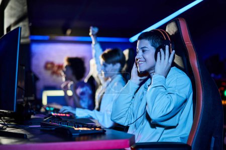 Fokus auf fröhliche junge Frau gewinnt Spiel neben verschiedenen Freundinnen, Cybersport-Spieler