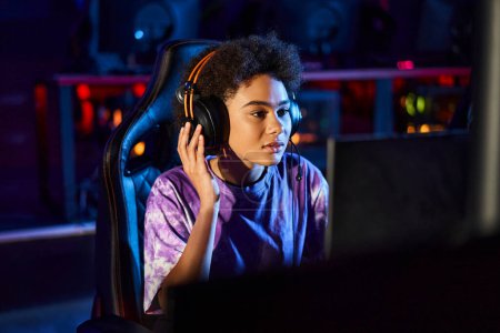 afrikanisch-amerikanischer Gamer mit Kopfhörern, der auf den Monitor schaut, während er über Spielstrategie, Cybersport nachdenkt