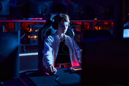 junger Gamer mit Kopfhörern, der auf den Computermonitor schaut, während er über Spielstrategie, Cybersport nachdenkt