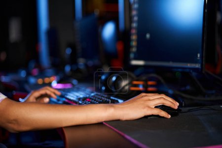 Foto de Recortado tiro de la mujer con el ratón de la computadora cerca del teclado iluminado durante el juego, cybersport - Imagen libre de derechos